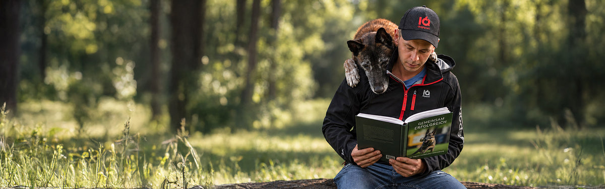Man and Malinois are looking into dog sport book together